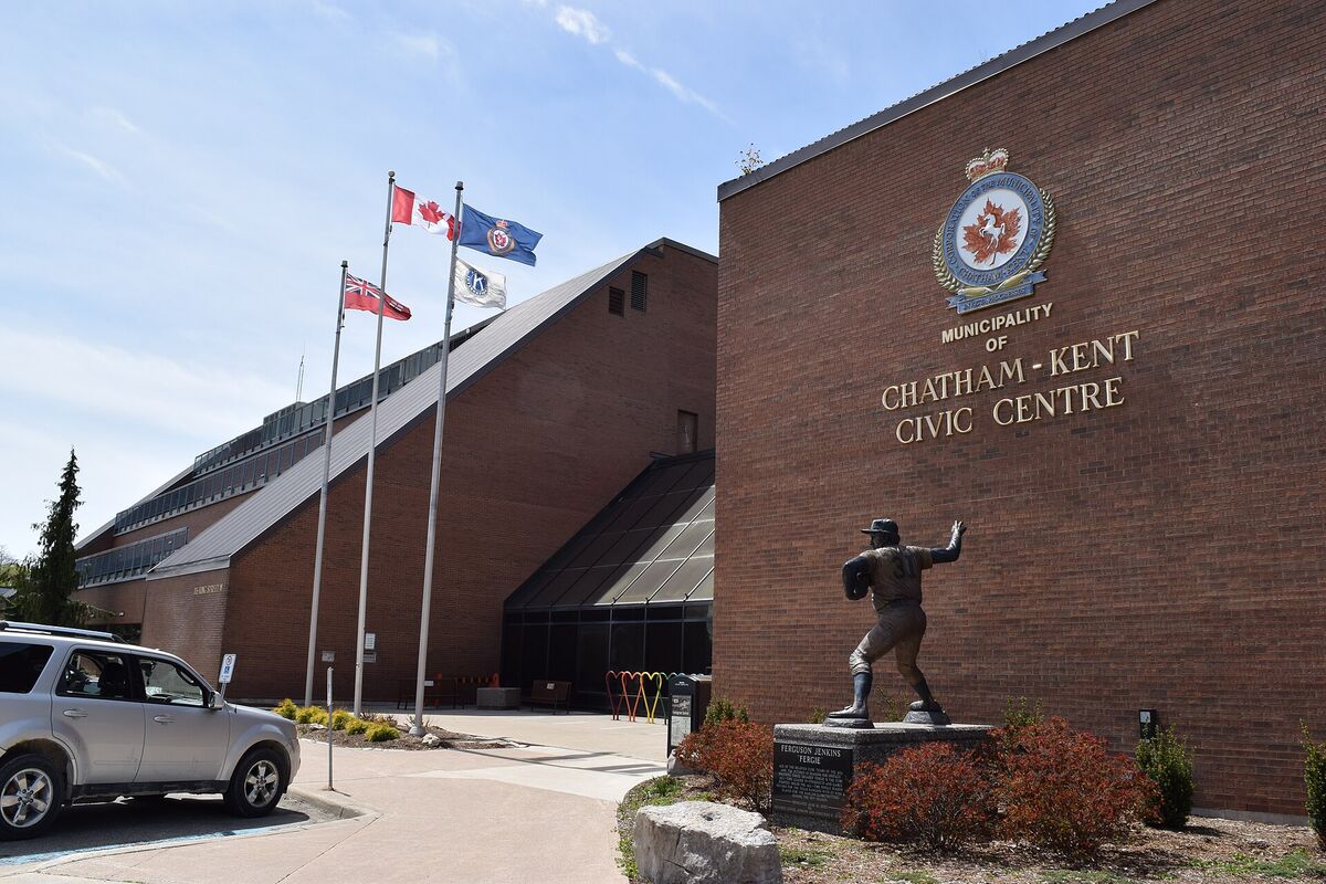 Brick exterior of the Chatham-Kent Civic Centre with flags and a statue of Ferguson Jenkins