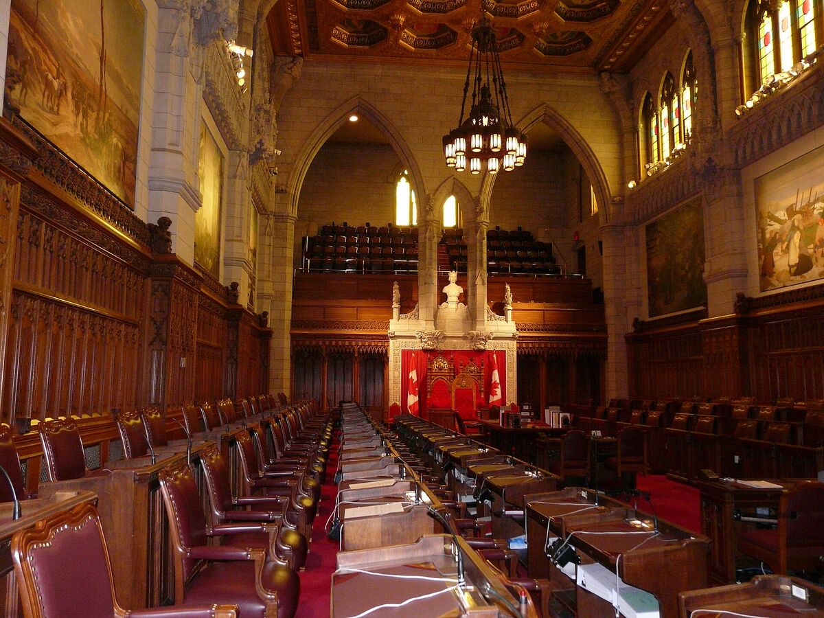 The Senate chamber in Canada's Parliament, with red carpet and wooden desks
