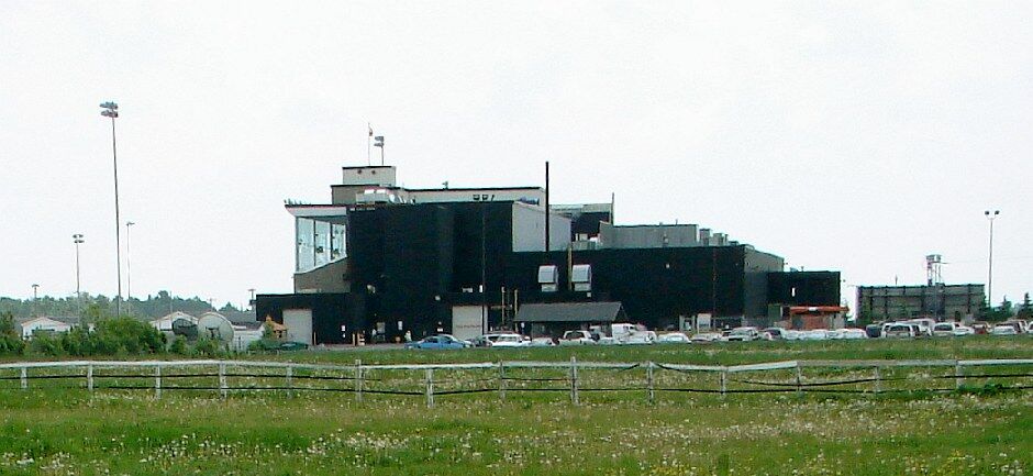 Low black casino and grandstand building behind a fenced field at the former Sudbury Downs racetrack