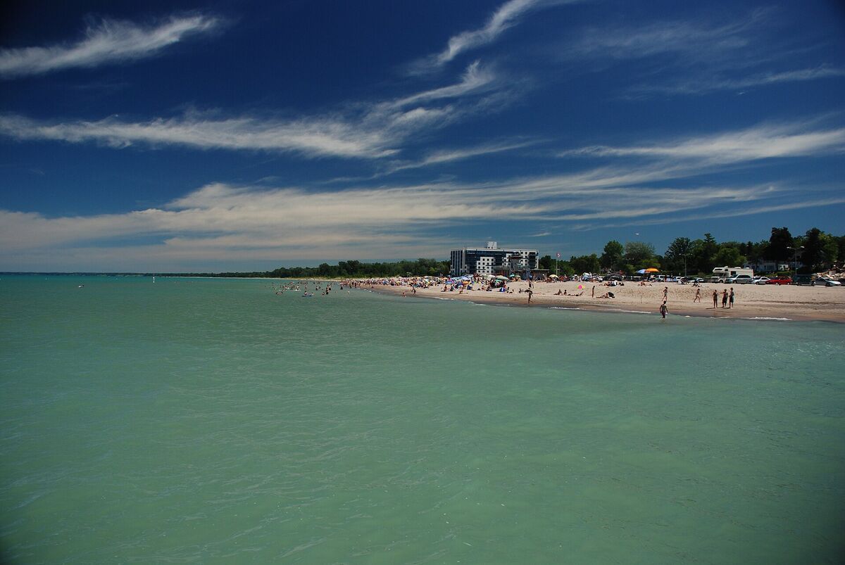 Sandy Grand Bend beach on Lake Huron with swimmers, turquoise water and a mid-rise building on the shore