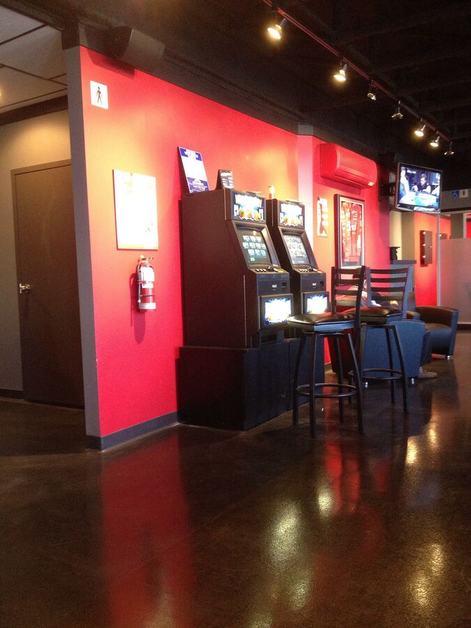 Two video lottery terminals against a red wall in a bar lounge
