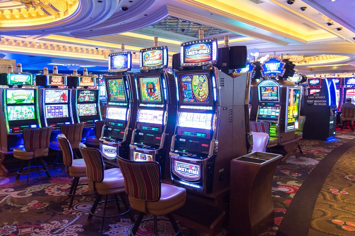 Rows of lit slot machines with stools on a casino floor