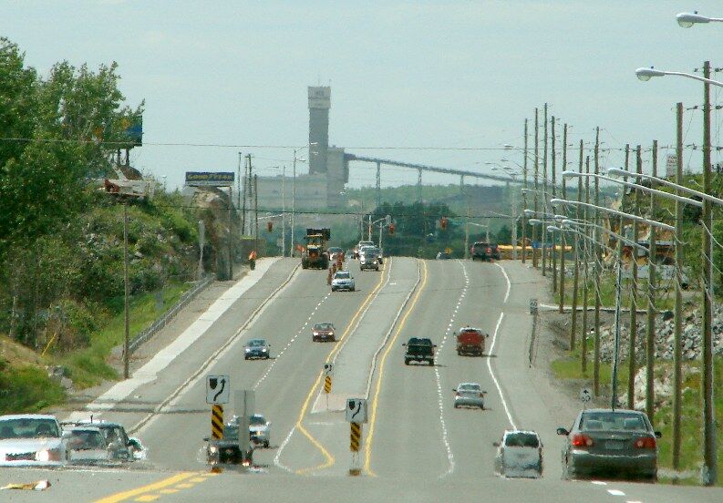 Traffic on the four-lane Kingsway in Sudbury with a mine headframe in the distance